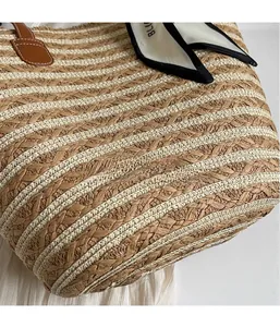 Detailed close-up of woven straw handbag texture with brown leather handle and floral silk scarf