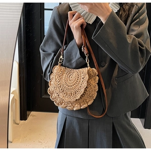 Détail d'un sac bandoulière tissé beige avec texture crochetée et bandoulière en cuir brun
