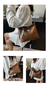 Detail of soft brown leather tote bag with silver triangle hardware and woven charm