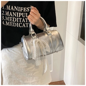 Detail of silver metallic Boston bag with lace bow and pearl chain charm