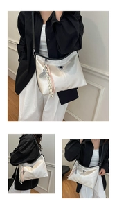 Detail of white satin tote bag featuring triangular logo and tennis racket tassel charm