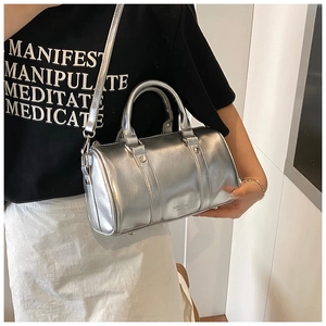 Detail of silver metallic Boston bag with detachable strap shown on a model