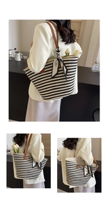 Detail of striped straw tote bag featuring leather handles and decorative BLIND silk scarf