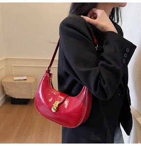 Chic red patent leather hobo bag with gold hardware styled on a black blazer