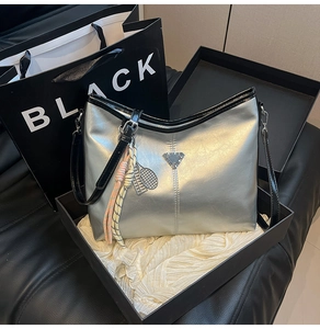 Detailed view of silver metallic tote bag with tennis racket charm and metal logo