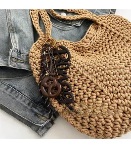 Gros plan détaillé du sac cabas tissé avec pendentif bretzel et lettres décoratives
