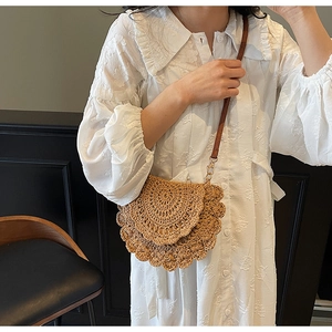 Détail d'un sac en paille tressée avec bords en pétales ondulés et bandoulière en cuir