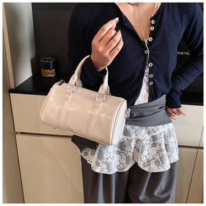 Close-up of cream white glossy leather Boston bag with metallic silver hardware details
