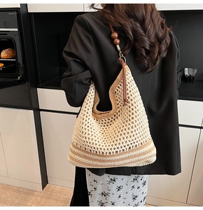 Dettaglio della borsa tote a righe intrecciata con tracolla in perline di legno sul modello