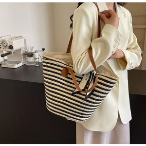 Detail of striped woven tote bag with brown leather handles and decorative silk scarf