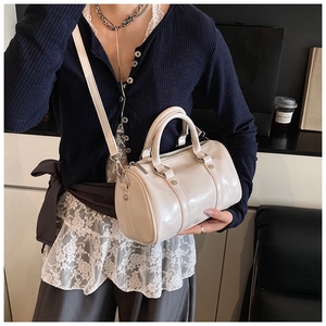 Detail view of cream Boston bowling bag with glossy synthetic leather and silver hardware