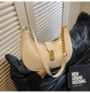 Detail shot of a creamy white crescent bag with gold chain and vintage metal buckle closure