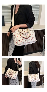 Detailed views of a white tote bag with red cherry prints and dual front pockets