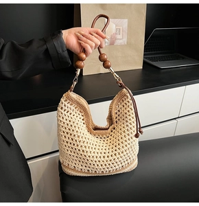 Dettaglio della borsa tote in maglia beige con manici in pelle e perle di legno