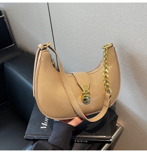 Detail of beige hobo bag showing golden thick chain decoration and metal push-lock closure