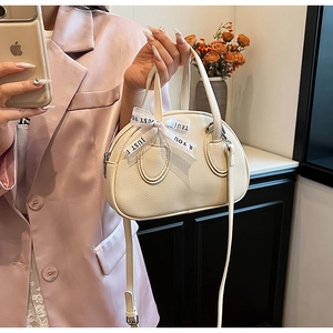 Detail view of cream bowling bag with lychee texture and decorative Just For You ribbon