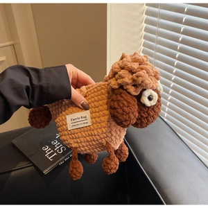 Close-up of handmade sheep-shaped knit bag showing textured brown wool and brand label