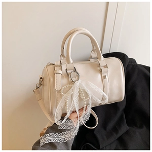 Close-up of cream Boston bag with delicate lace bow and pearl charm details