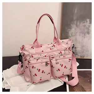 Detailed view of pink tote bag with cherry prints featuring front zip pockets and straps
