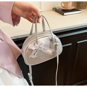 Detailed view of silver metallic Boston handbag with white ribbon and leather texture