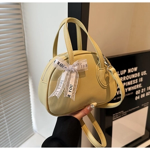 Detail of yellow pebbled leather bowling bag with printed silk ribbon and gold hardware