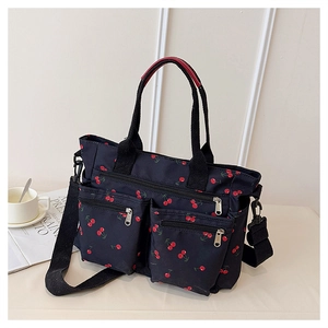 Detailed view of the red cherry print on black tote bag with dual front zipper pockets