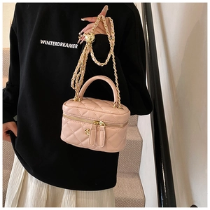 Pink quilted crossbody box bag with gold flower detail and leather chain strap on model
