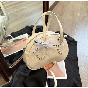Close-up of beige lychee texture handbag with decorative ribbon and adjustable shoulder strap