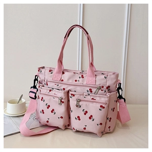 Detail view of pink canvas tote bag with cherry print and dual front zipper pockets