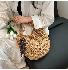 Détail d'un sac cabas en maille tressée beige avec un pendentif décoratif élégant