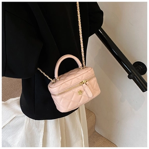 Pink quilted box bag with gold camellia floral detail and chain strap worn by a model