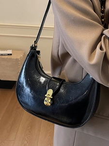 Chic black patent leather crescent underarm bag with vintage gold buckle closure