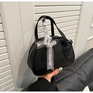 Close-up of black litchi grain leather bowling bag with silk ribbon detail