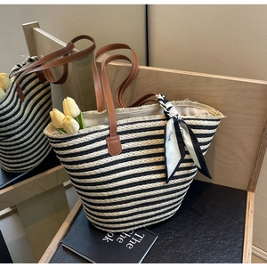 Detail view of a striped woven beach tote with brown straps and a decorative silk scarf