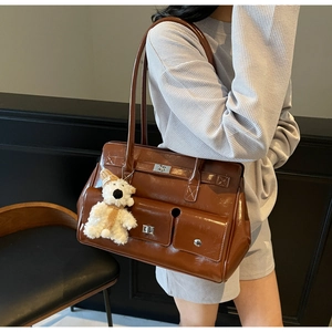 Detail view of brown patent leather tote bag with pockets and cute white bear charm decoration