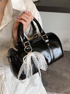 Fashionable black Boston barrel handbag with a white lace bow and pearl charm detail