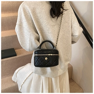 Quilted black mini box bag with golden floral hardware and chain strap on shoulder