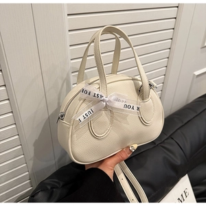 Detail view of cream bowling bag with lychee grain leather and decorative ribbon
