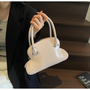 Detail of light pink patent leather shell bag with wavy design and silver rivets