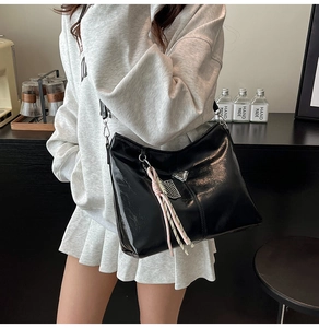 Close-up of black glossy patent leather tote bag with iconic triangle metal logo