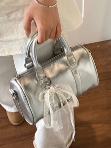 Silver metallic Boston bag with lace bow and pearl charm decoration in handheld view
