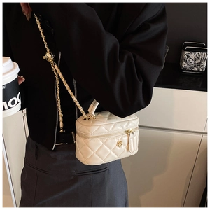 Close-up of quilted white leather mini bag featuring gold flower logo and woven chain