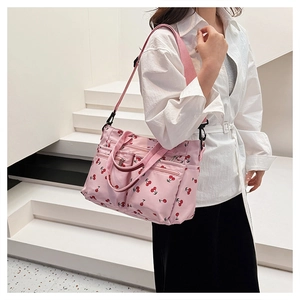 Detailed view of pink nylon tote bag with cherry print featuring three front zipper pockets