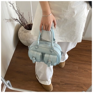 Detailed view of light blue bowling handbag featuring front flap pockets and silver hardware