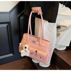 Detail of pink patent leather shoulder bag with silver buckle and plush bear charm