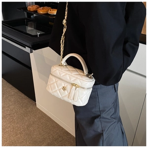 Detail of white quilted crossbody bag featuring a golden camellia flower and chain strap