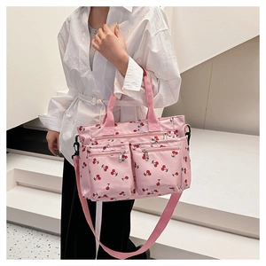 Pink canvas tote with cherry prints featuring front zip pockets and wide strap