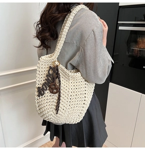 Vue détaillée de la texture du sac cabas tissé crème et du pendentif en lettre marron