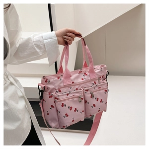 Close-up of pink cherry print tote bag showing multiple front zipper pockets and fabric texture