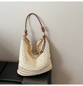 Dettaglio della borsa tote intrecciata con motivo traforato, manici marroni e perline